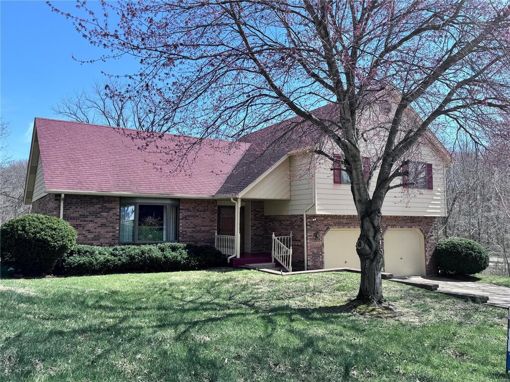 tri-level home featuring brick siding, concrete driveway, a front yard, and a garage