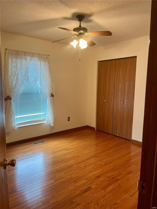 unfurnished bedroom featuring ceiling fan, light wood-type flooring, and a textured ceiling