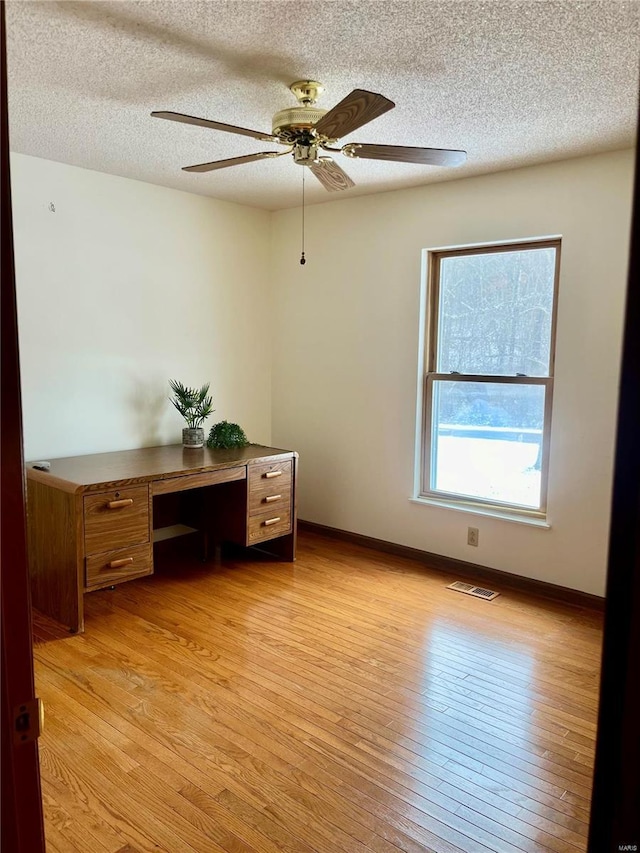 office space with light hardwood / wood-style floors, ceiling fan, and a textured ceiling