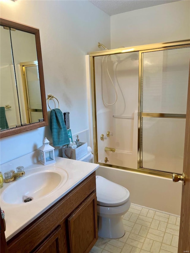 full bathroom featuring a textured ceiling, toilet, vanity, and combined bath / shower with glass door