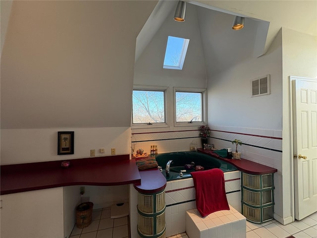 tiled dining area featuring a skylight and high vaulted ceiling