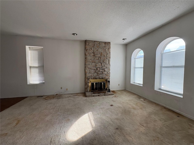 unfurnished living room featuring light colored carpet, a fireplace, and a textured ceiling