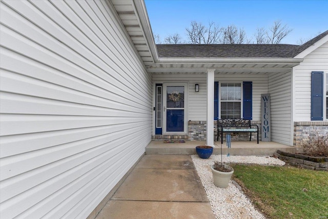 entrance to property featuring stone siding, a porch, and a shingled roof