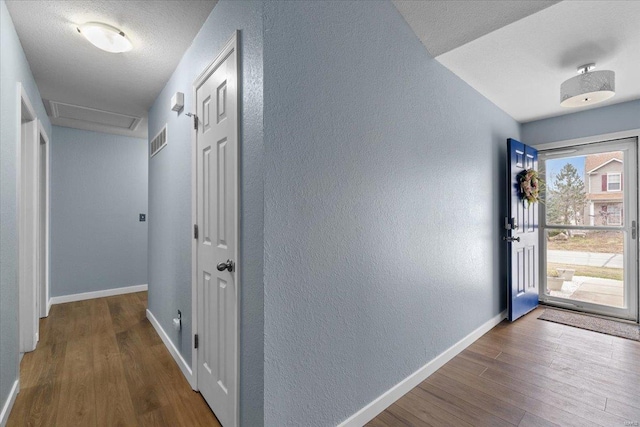 foyer with baseboards, visible vents, a textured wall, wood finished floors, and a textured ceiling