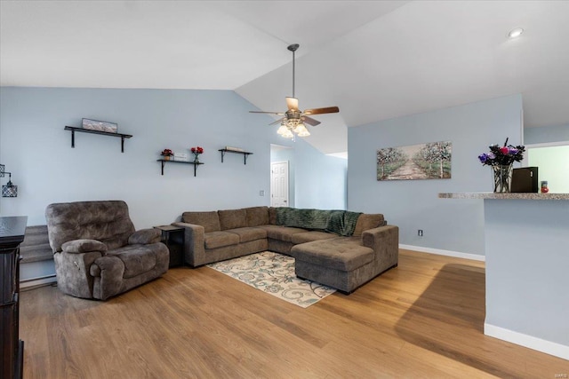 living area with a ceiling fan, vaulted ceiling, baseboards, and wood finished floors