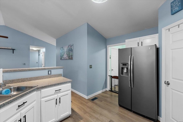 kitchen with light wood finished floors, visible vents, white cabinets, vaulted ceiling, and stainless steel refrigerator with ice dispenser