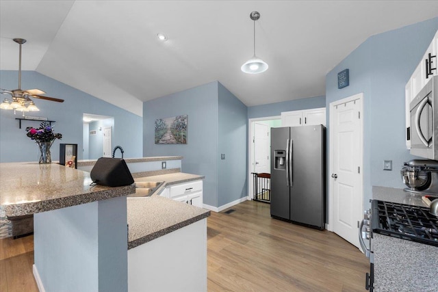 kitchen with light wood finished floors, white cabinets, lofted ceiling, hanging light fixtures, and stainless steel appliances