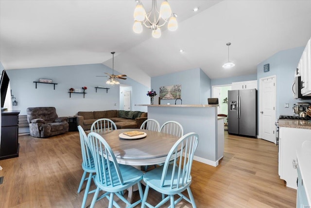 dining area with a ceiling fan, vaulted ceiling, and light wood-style flooring