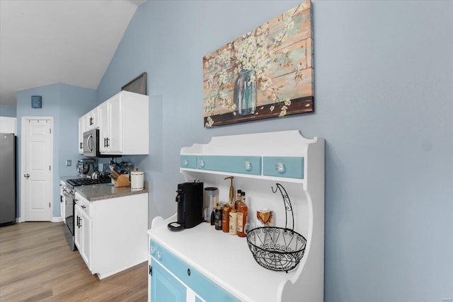 kitchen featuring lofted ceiling, stainless steel appliances, light wood-type flooring, and white cabinetry