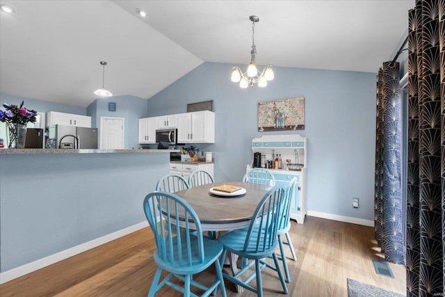 dining area with baseboards, visible vents, lofted ceiling, wood finished floors, and a notable chandelier