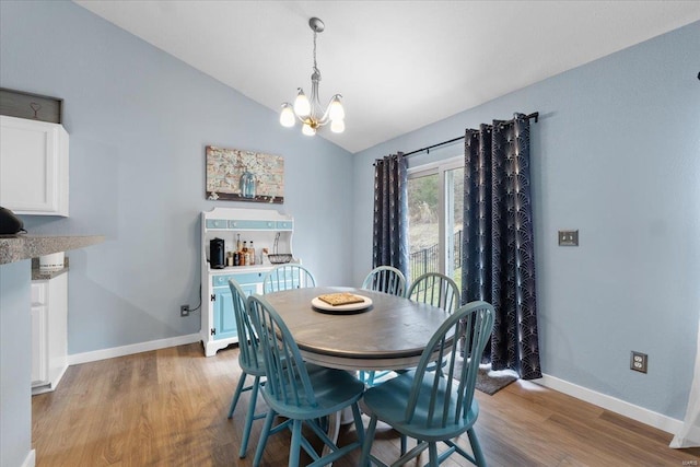 dining space with lofted ceiling, a notable chandelier, light wood-style flooring, and baseboards