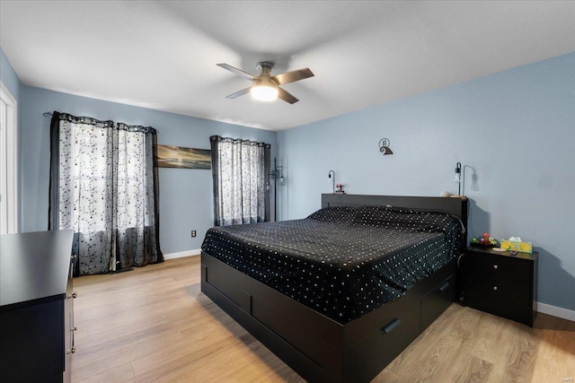 bedroom featuring light wood-style flooring, baseboards, and ceiling fan