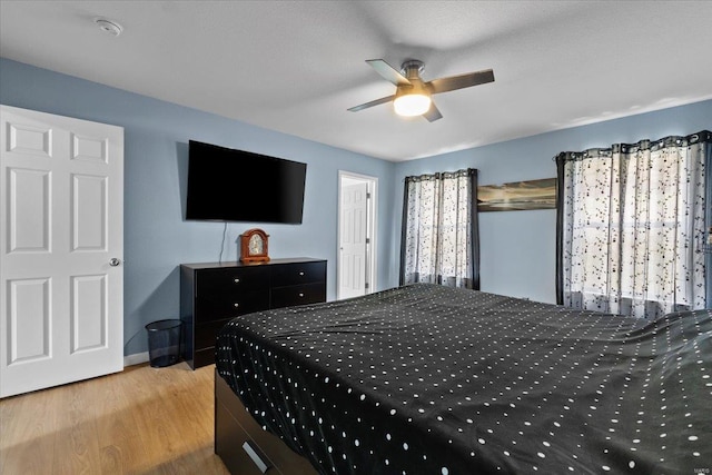 bedroom featuring a ceiling fan, baseboards, and wood finished floors