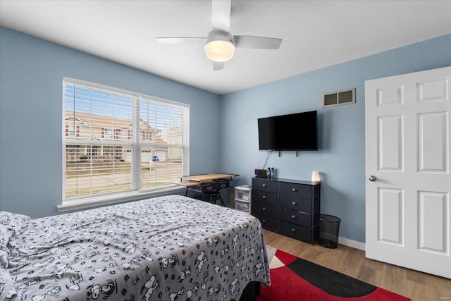 bedroom with visible vents, ceiling fan, baseboards, and wood finished floors