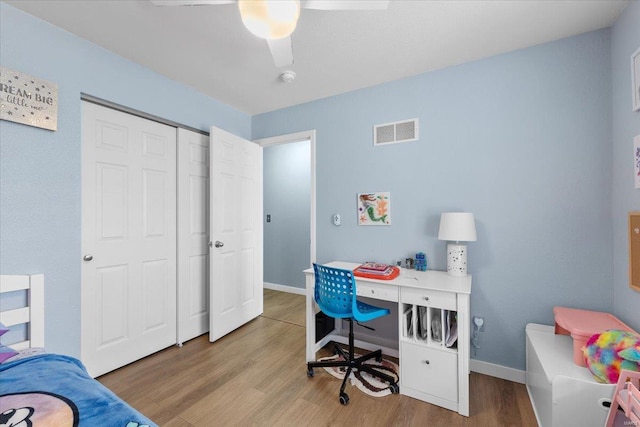 bedroom with a closet, wood finished floors, visible vents, and baseboards