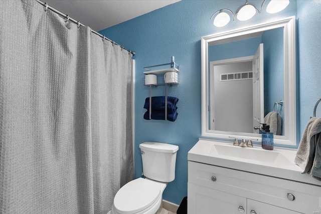 bathroom featuring visible vents, a textured wall, vanity, and toilet