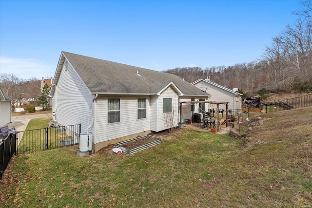 rear view of property with a yard, a shingled roof, a patio area, and a fenced backyard