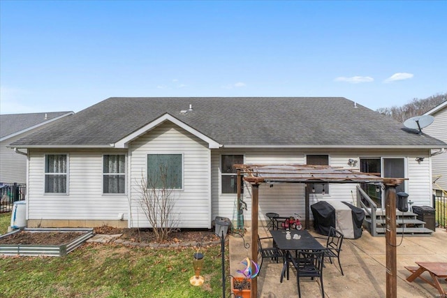 back of property featuring a garden, roof with shingles, and a patio