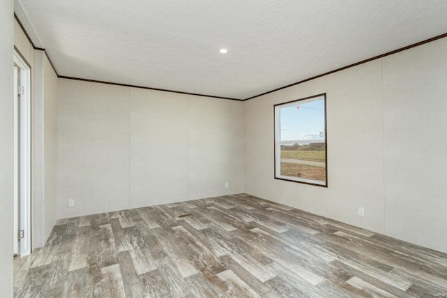 empty room featuring crown molding, a textured ceiling, and wood finished floors