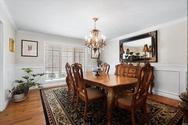 dining space with a wainscoted wall, ornamental molding, and wood finished floors