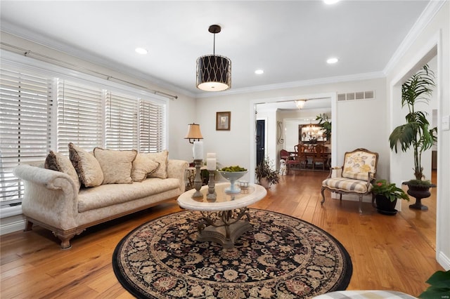 living area featuring ornamental molding, recessed lighting, visible vents, and wood finished floors