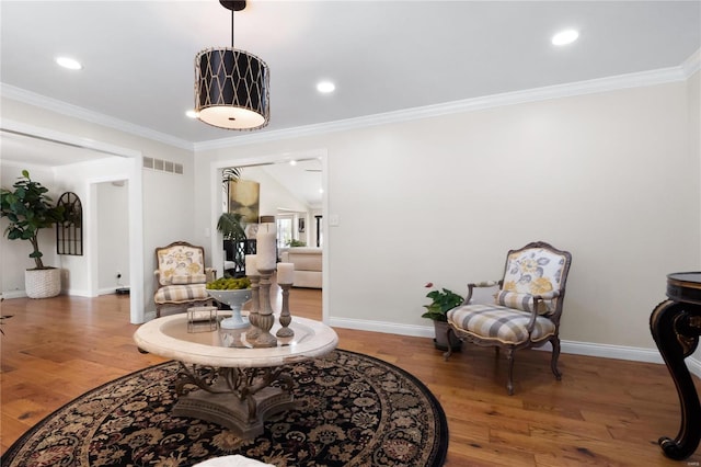 sitting room with visible vents, wood finished floors, and ornamental molding