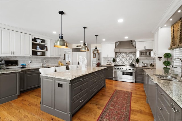 kitchen featuring premium range hood, a sink, white cabinetry, appliances with stainless steel finishes, and a center island