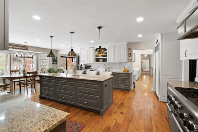 kitchen featuring a center island, open shelves, hanging light fixtures, gray cabinetry, and white cabinetry