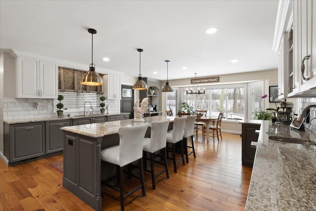 kitchen featuring a kitchen island, white cabinets, a sink, and decorative light fixtures