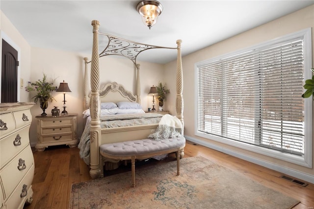 bedroom with baseboards, visible vents, and wood finished floors