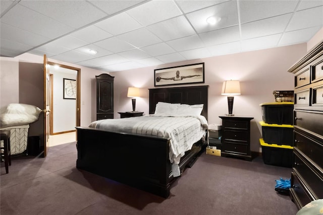 bedroom with dark colored carpet and a drop ceiling