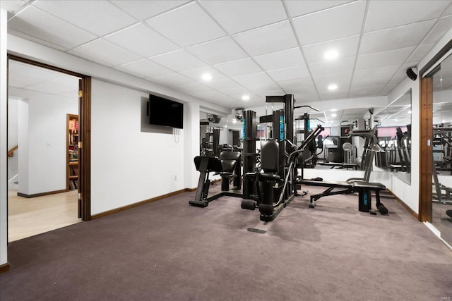 exercise area with a drop ceiling, carpet, and baseboards