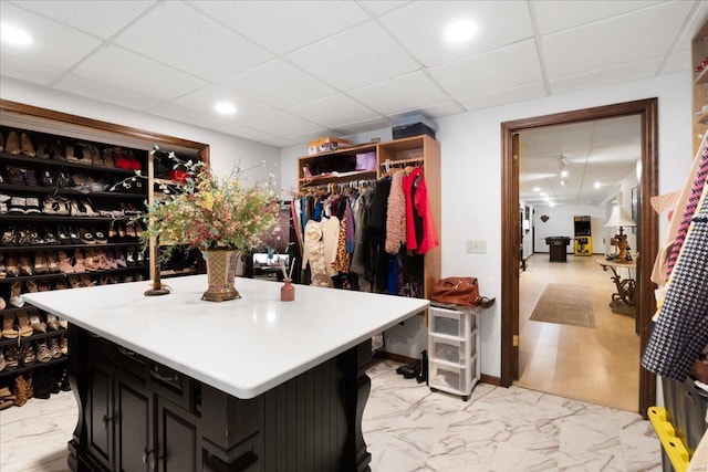 walk in closet featuring a paneled ceiling and marble finish floor