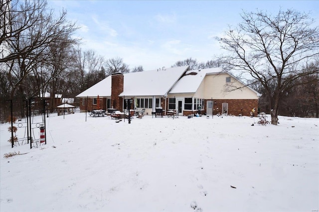 snow covered rear of property featuring a chimney