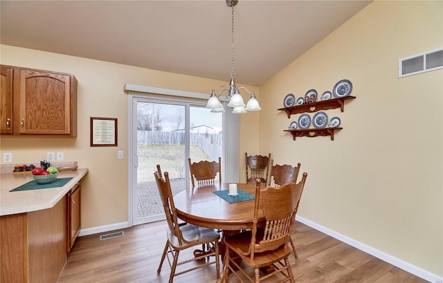 dining space featuring vaulted ceiling, a chandelier, and light hardwood / wood-style flooring