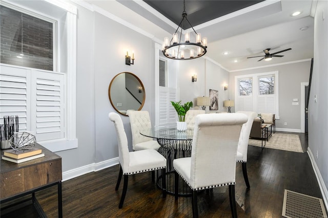 dining room with ornamental molding, dark hardwood / wood-style floors, ceiling fan with notable chandelier, and a tray ceiling