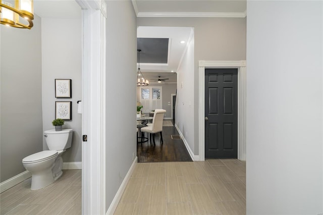 corridor with crown molding, a notable chandelier, and light hardwood / wood-style floors