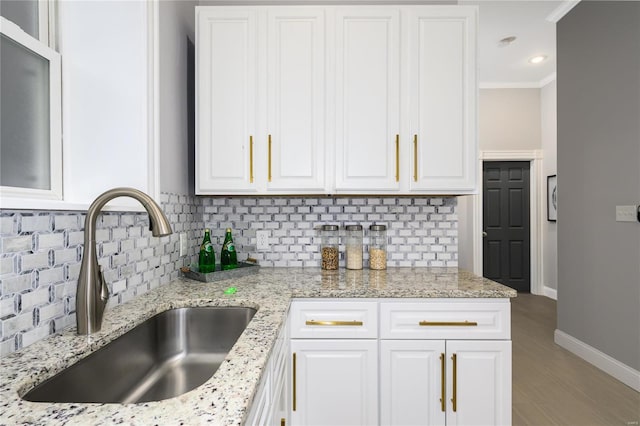 kitchen featuring white cabinetry, light stone countertops, and sink