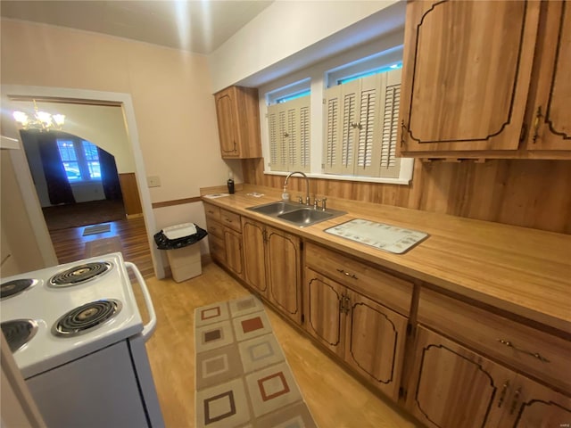 kitchen featuring sink, hanging light fixtures, a notable chandelier, light wood-type flooring, and electric stove