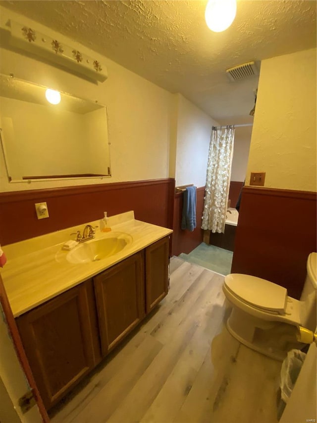 bathroom featuring hardwood / wood-style floors, vanity, a textured ceiling, toilet, and walk in shower