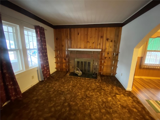 carpeted living room featuring a brick fireplace and wood walls