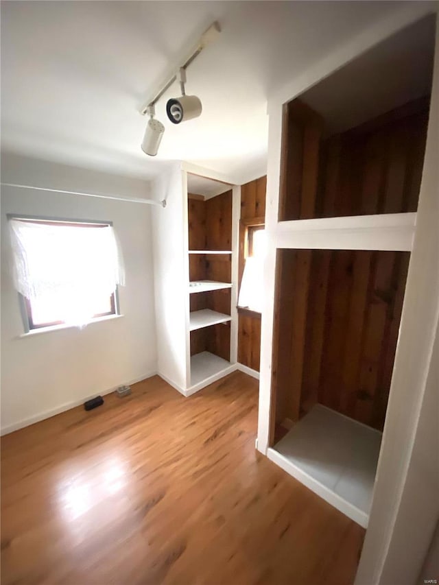 unfurnished bedroom featuring hardwood / wood-style floors and track lighting