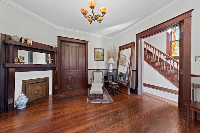 living area with crown molding, wood finished floors, stairway, a brick fireplace, and an inviting chandelier