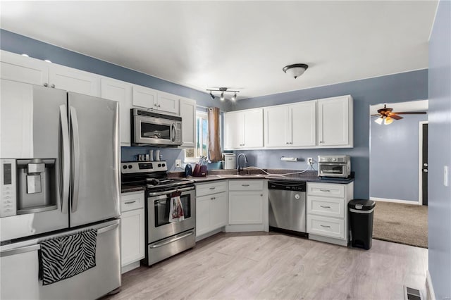 kitchen with dark countertops, white cabinetry, stainless steel appliances, and a sink