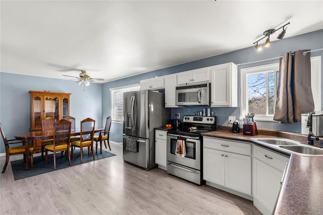 kitchen featuring ceiling fan, stainless steel appliances, white cabinets, light wood finished floors, and dark countertops