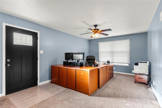 office space with light carpet, a ceiling fan, and baseboards