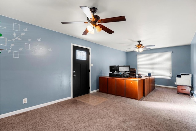 office space featuring a ceiling fan, light carpet, plenty of natural light, and baseboards