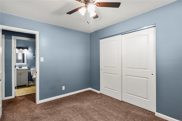 unfurnished bedroom with a sink, baseboards, dark colored carpet, and a closet