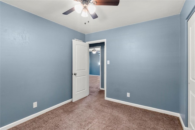 carpeted empty room with a ceiling fan and baseboards