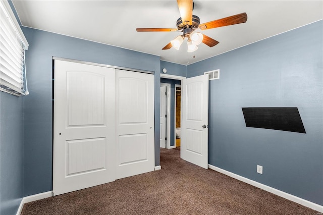 unfurnished bedroom with a closet, visible vents, dark carpet, ceiling fan, and baseboards